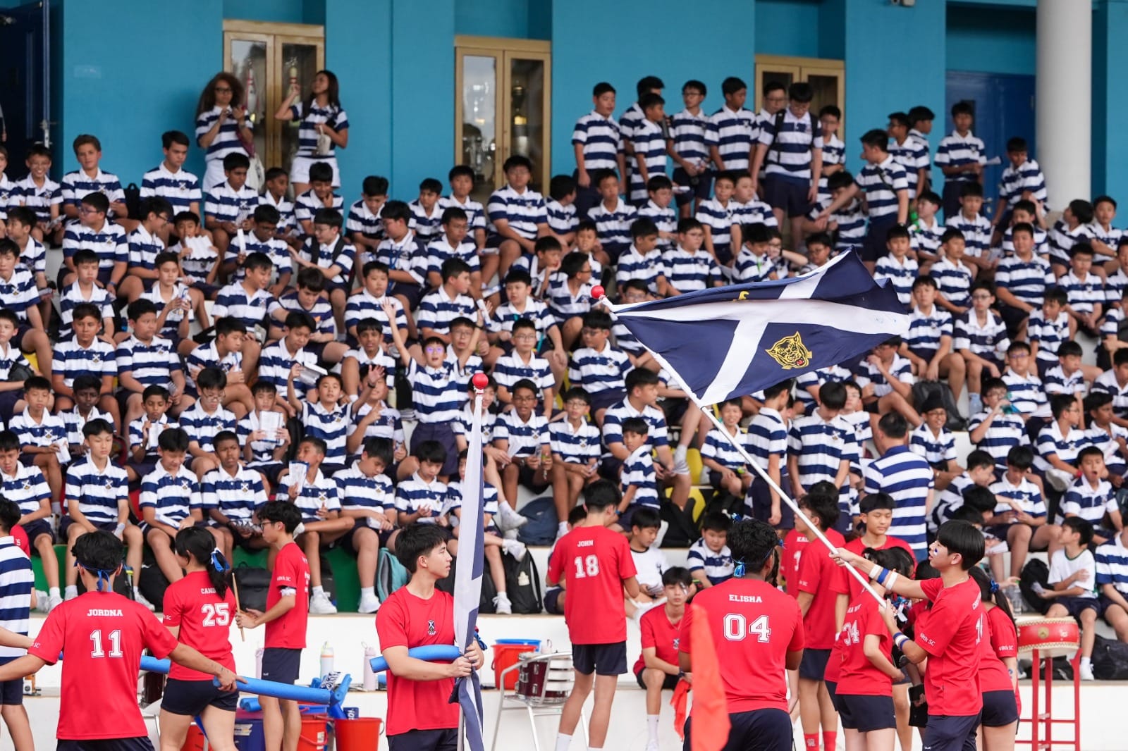 Group of boys in blue and white stripes cheering for their team in the stands